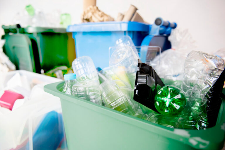 green recycling bin overflowing with plastic bottles